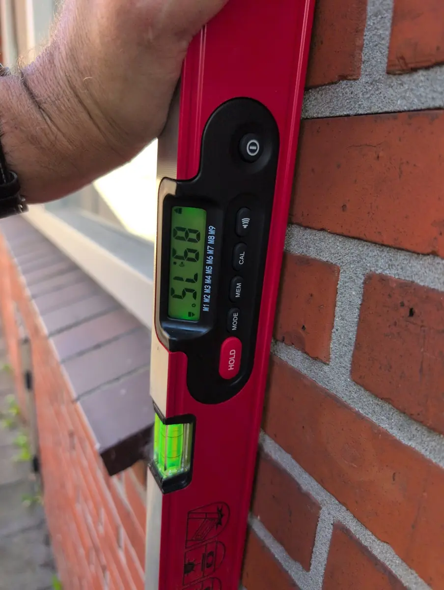 Digitale hellingsmeter tegen een gemetselde gevel