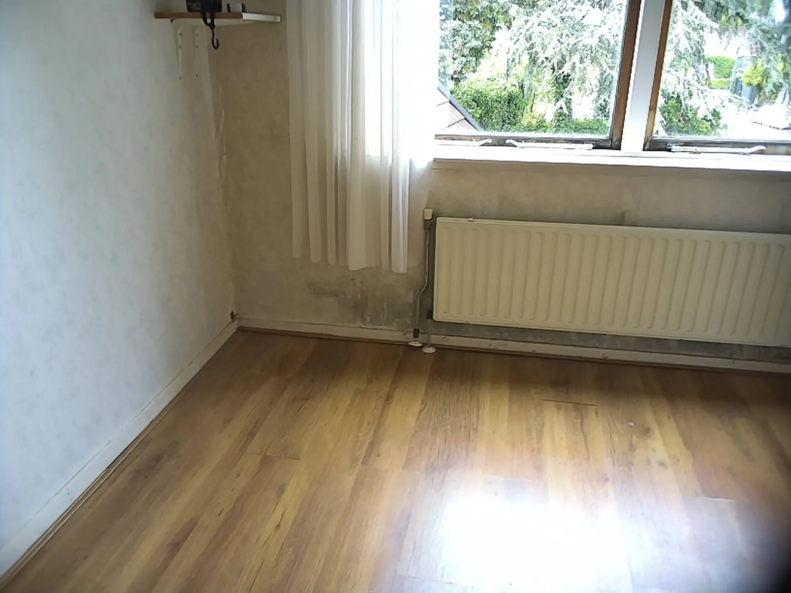 Visuele opname van vochtsporen onder een raam en naast een radiator