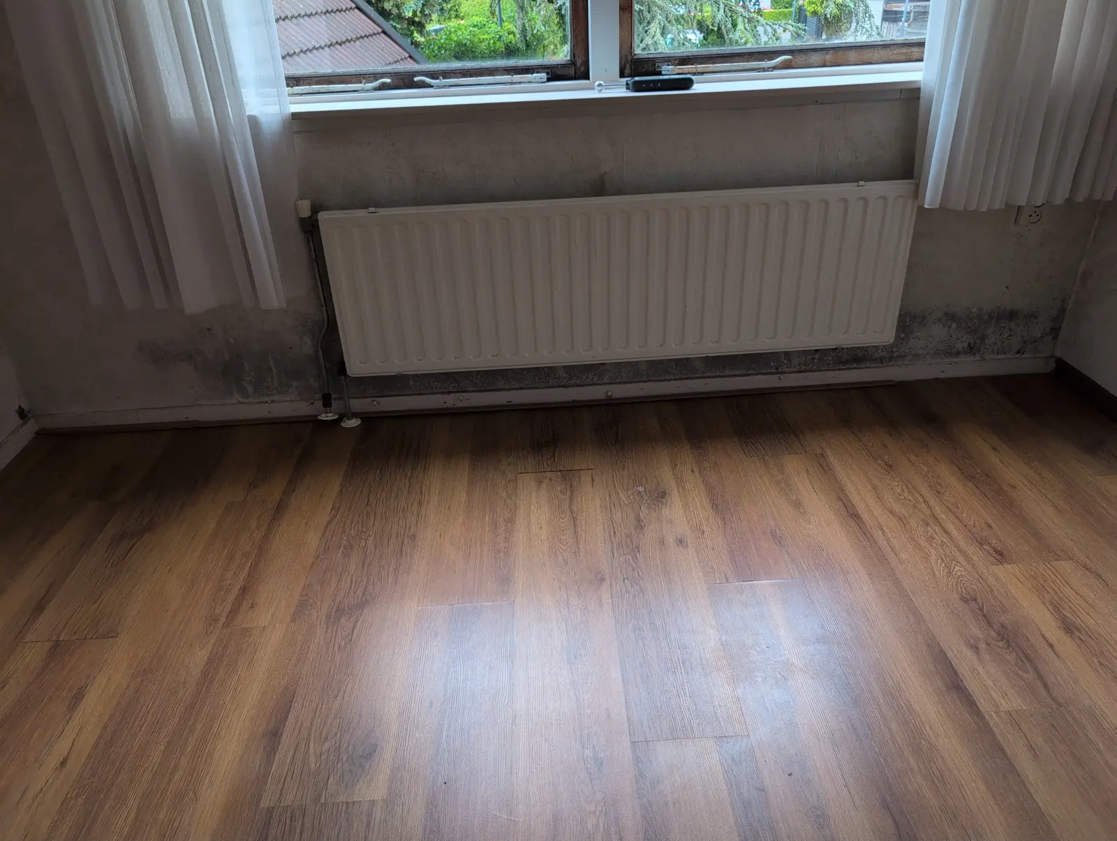 Vochtsporen onder een raam en naast een radiator
